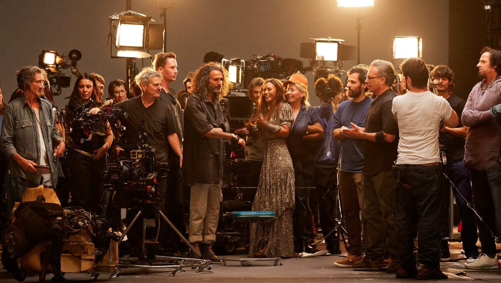 Full camera, lighting, and production crew gathered on a studio set between takes