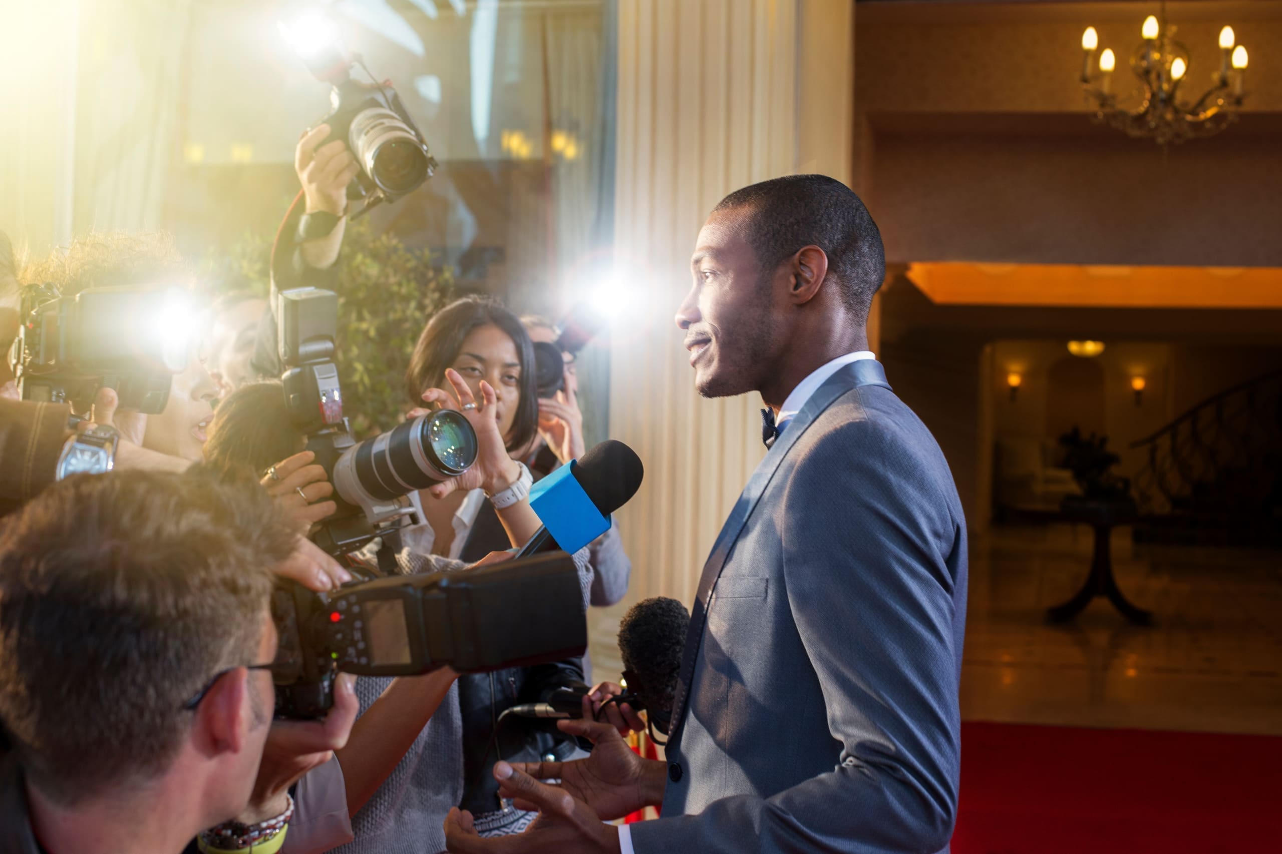 Guest interviewed by press photographers at an indoor red carpet event